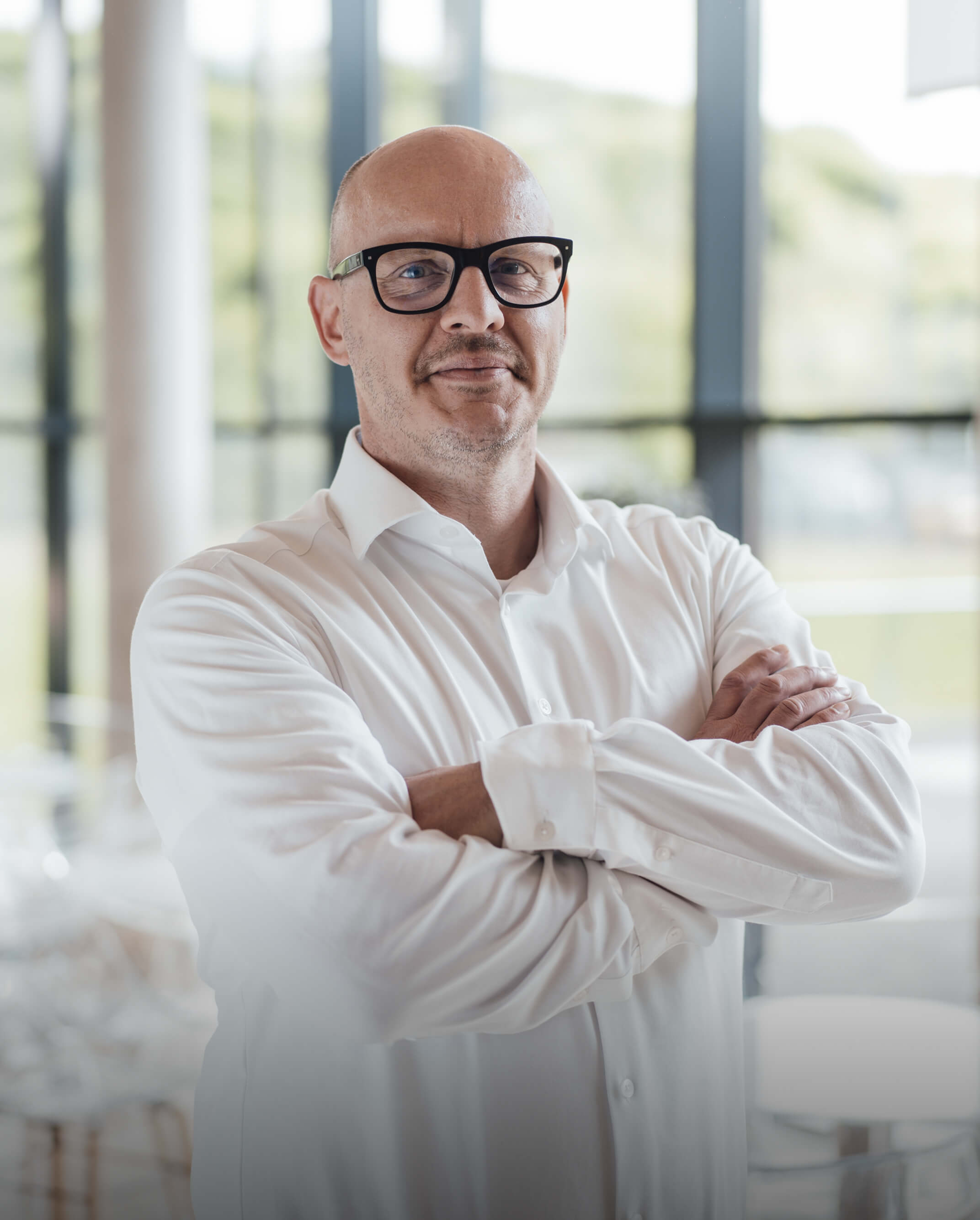 Mitarbeiter im weißen Hemd mit verschränkten Armen – Selbstbewusstsein und Erfahrung im BOS-Team